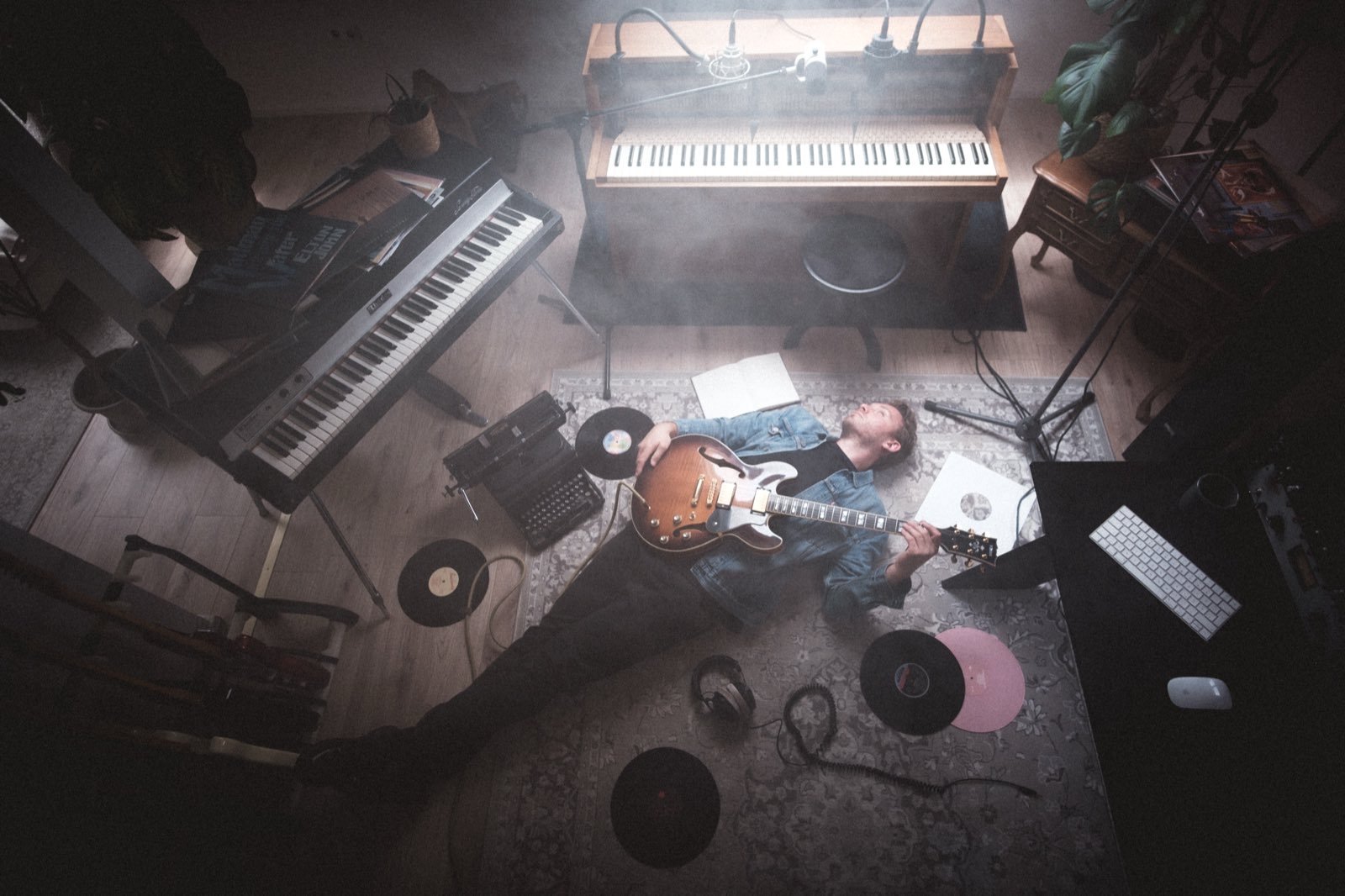 Blick von oben auf das Dachgeschoss-Studio: Phil Young liegt mit einer Halbakustik-Gitarre zwischen Klavier, Stagepiano und Schallplatten.