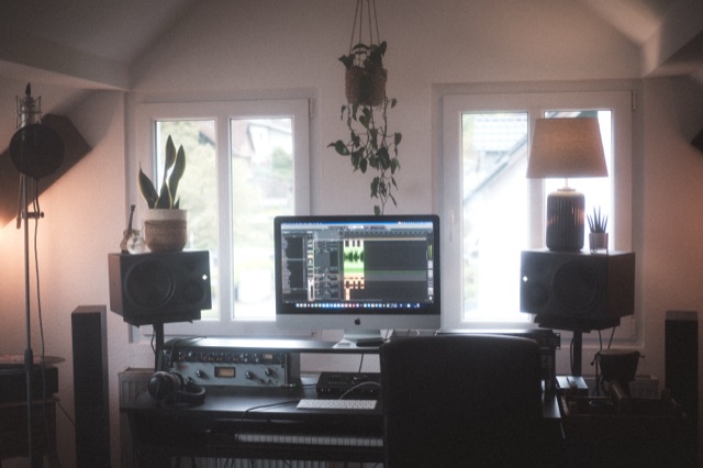 Der Arbeitsplatz mit iMac, geöffneter DAW, Neumann-Monitoren und Outboard-Rack.